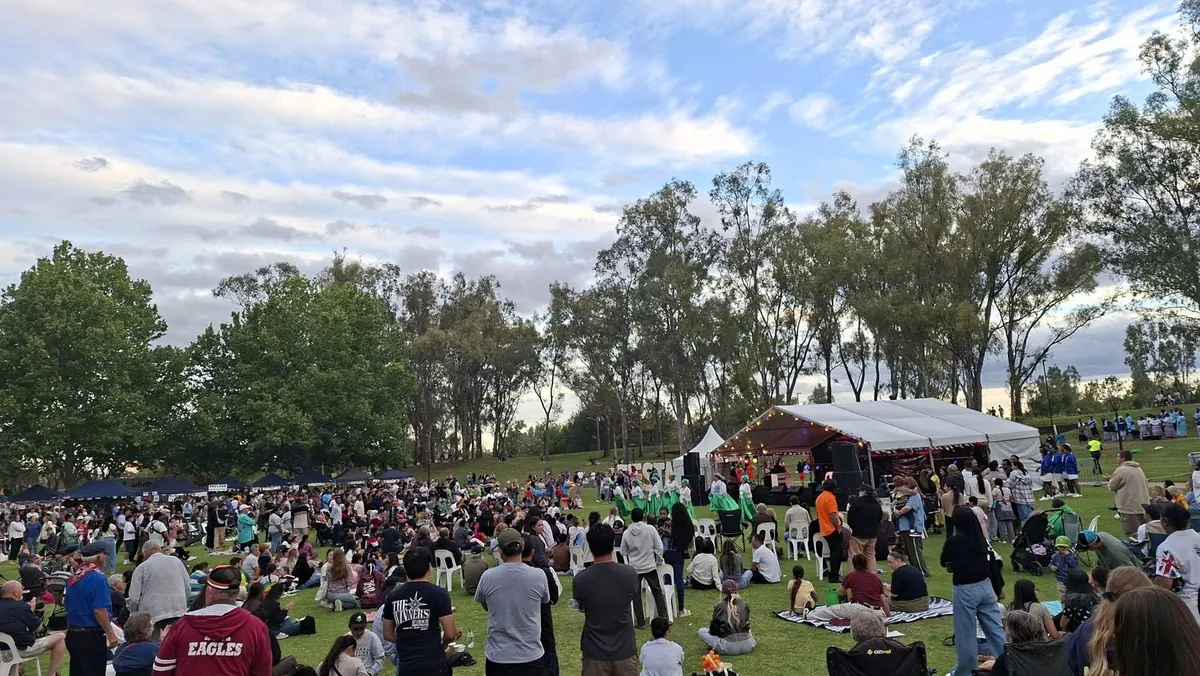 Dancers in green skirts performing in front of the main stage at Fiesta La Peel while a crowd watches