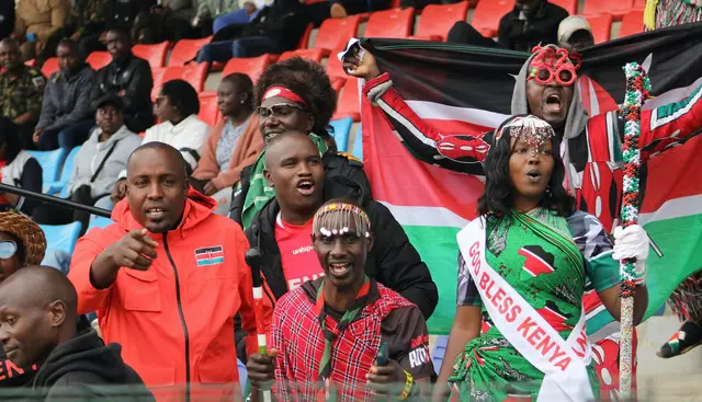 Fans waving Kenyan flags at a sporting event